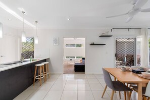 Une cuisine moderne dotée d’un îlot central, de tabourets de bar et d’un coin repas avec une table et des chaises.