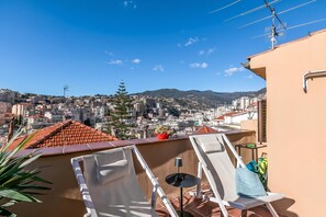 A rooftop terrace with white lounge chairs, a small table, and a potted plant. - Piccola Pigna - Terrazza Vista Mare Sanremo Studio, Sanremo, Italy (Sanremo)