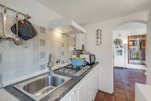 A modern kitchen with a stainless steel sink, a gas stove, and a blue pot on the counter. - Piccola Pigna - Terrazza Vista Mare Sanremo Studio, Sanremo, Italy (Sanremo)
