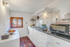 A compact kitchen with white cabinets, a built-in oven, a toaster, and a window with a view of buildings. - Piccola Pigna - Terrazza Vista Mare Sanremo Studio, Sanremo, Italy (Sanremo)