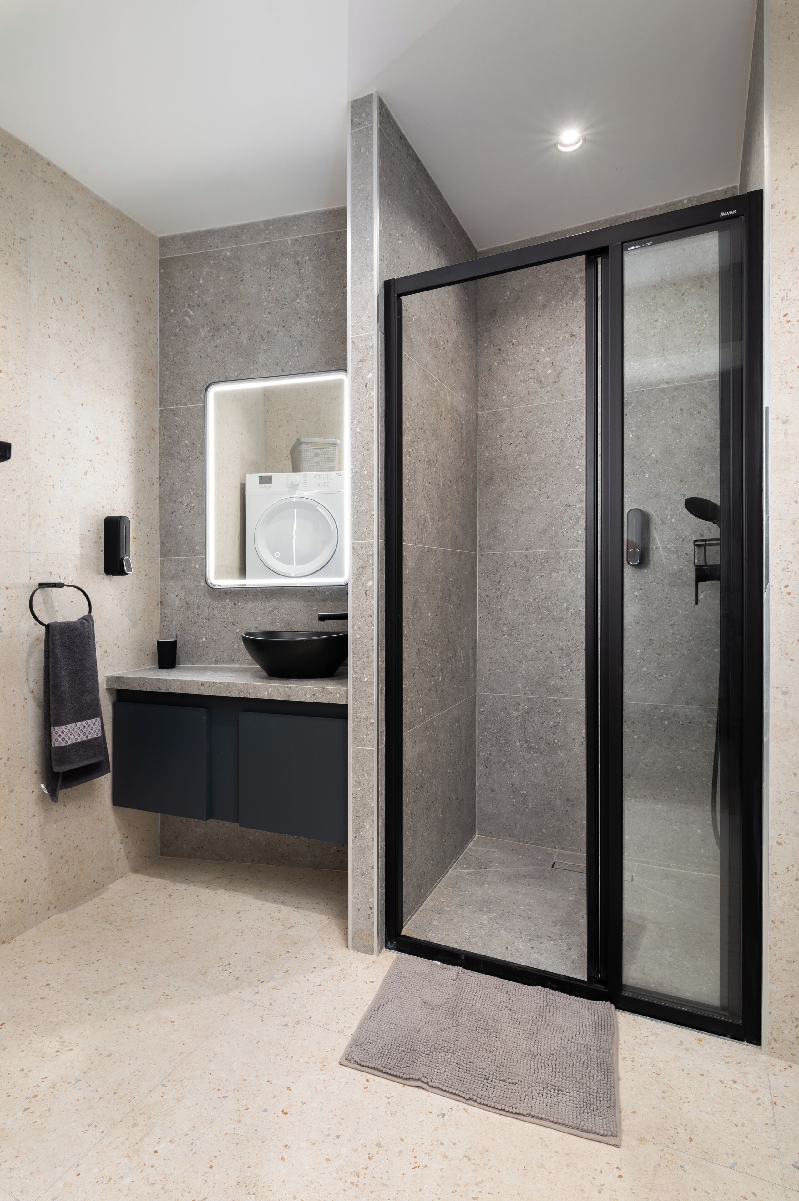 A modern bathroom with a glass shower enclosure, a sink with a black basin, and a towel rack with a towel.