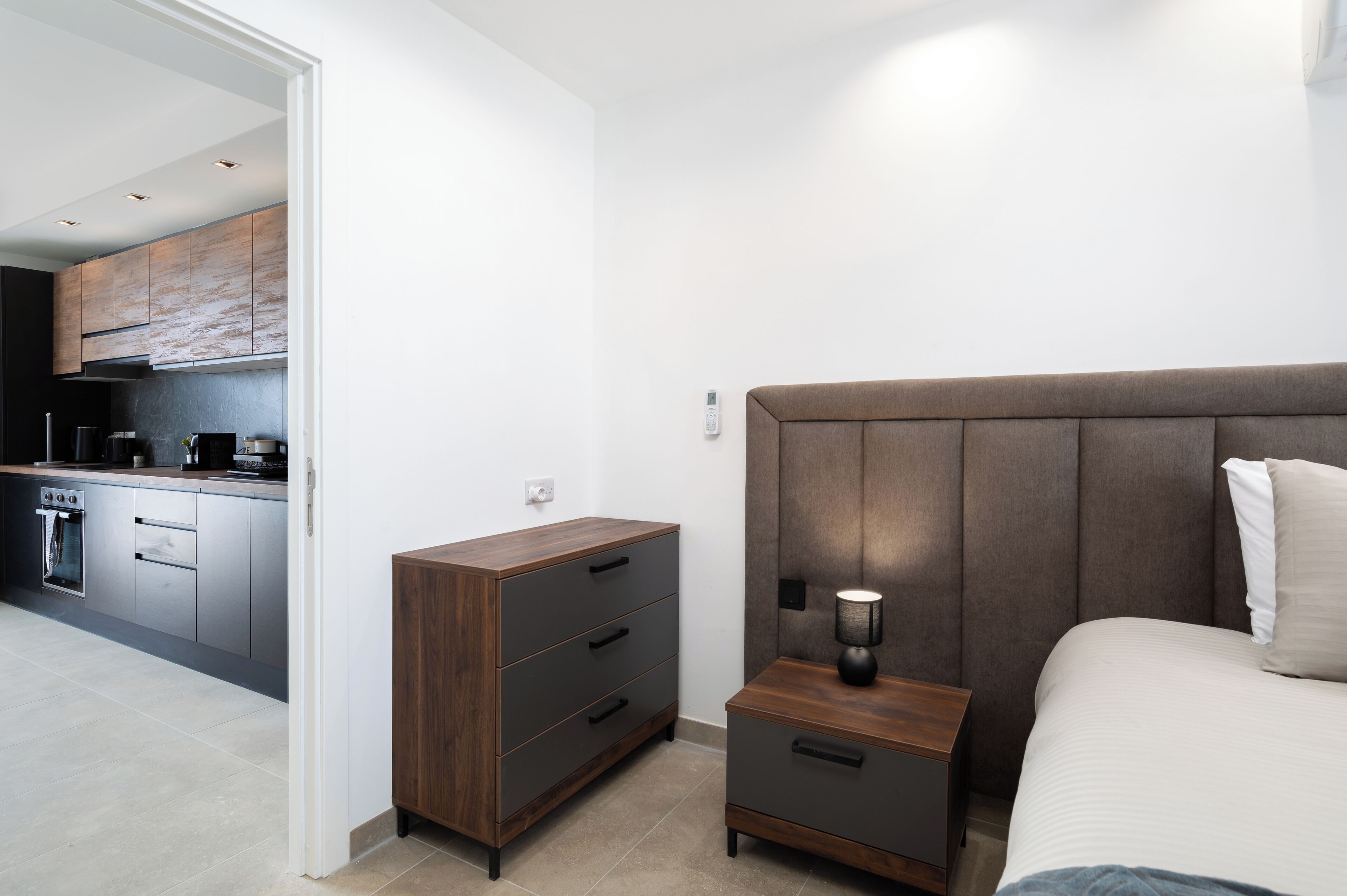 A modern bedroom with a large bed, a bedside table with a lamp, and a wooden nightstand.