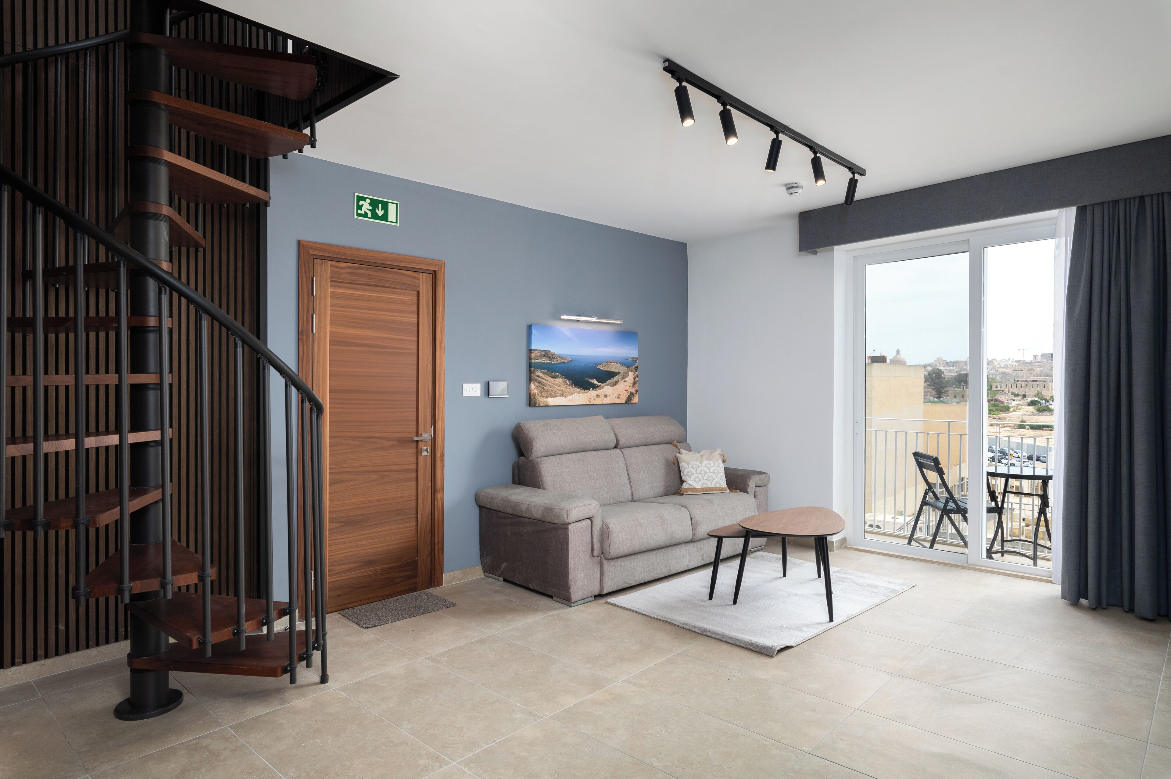 Ein modernes Wohnzimmer mit einem grauen Sofa, einem kleinen runden Tisch und einer Treppe mit Holzwertungen.