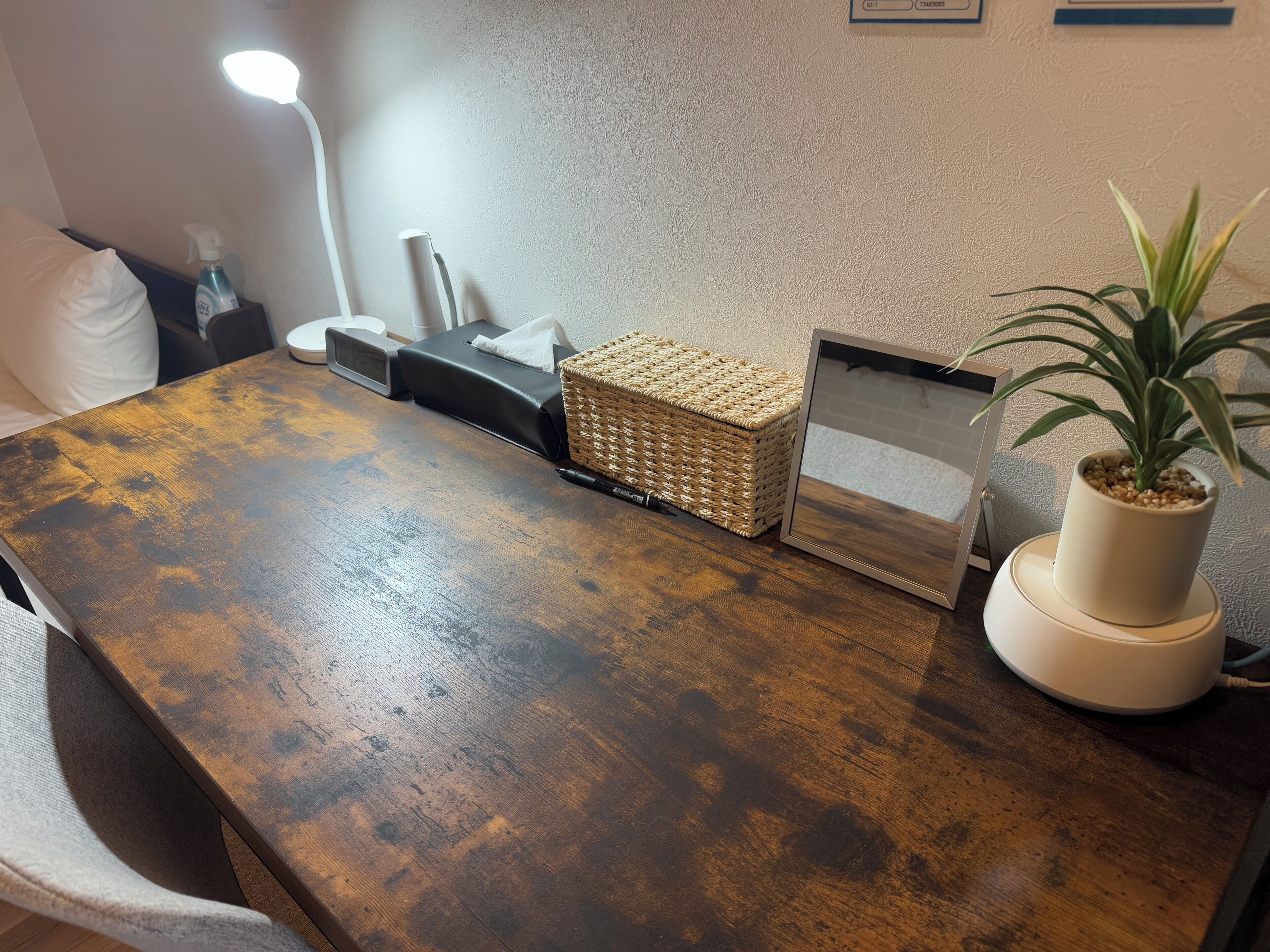 A wooden table with a woven basket, a potted plant, and a lamp.