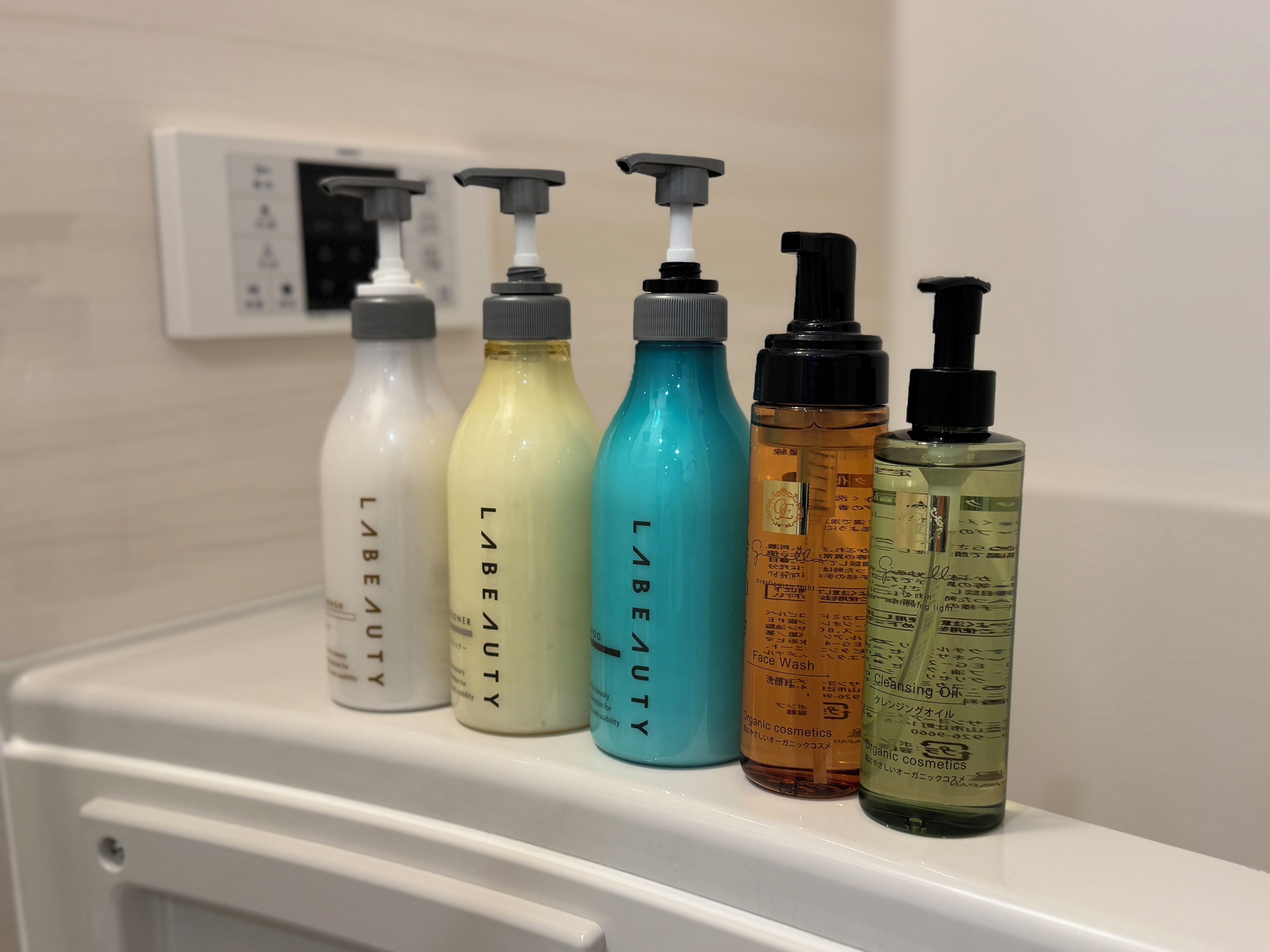 Una fila de botellas de cosméticos sobre un estante blanco.