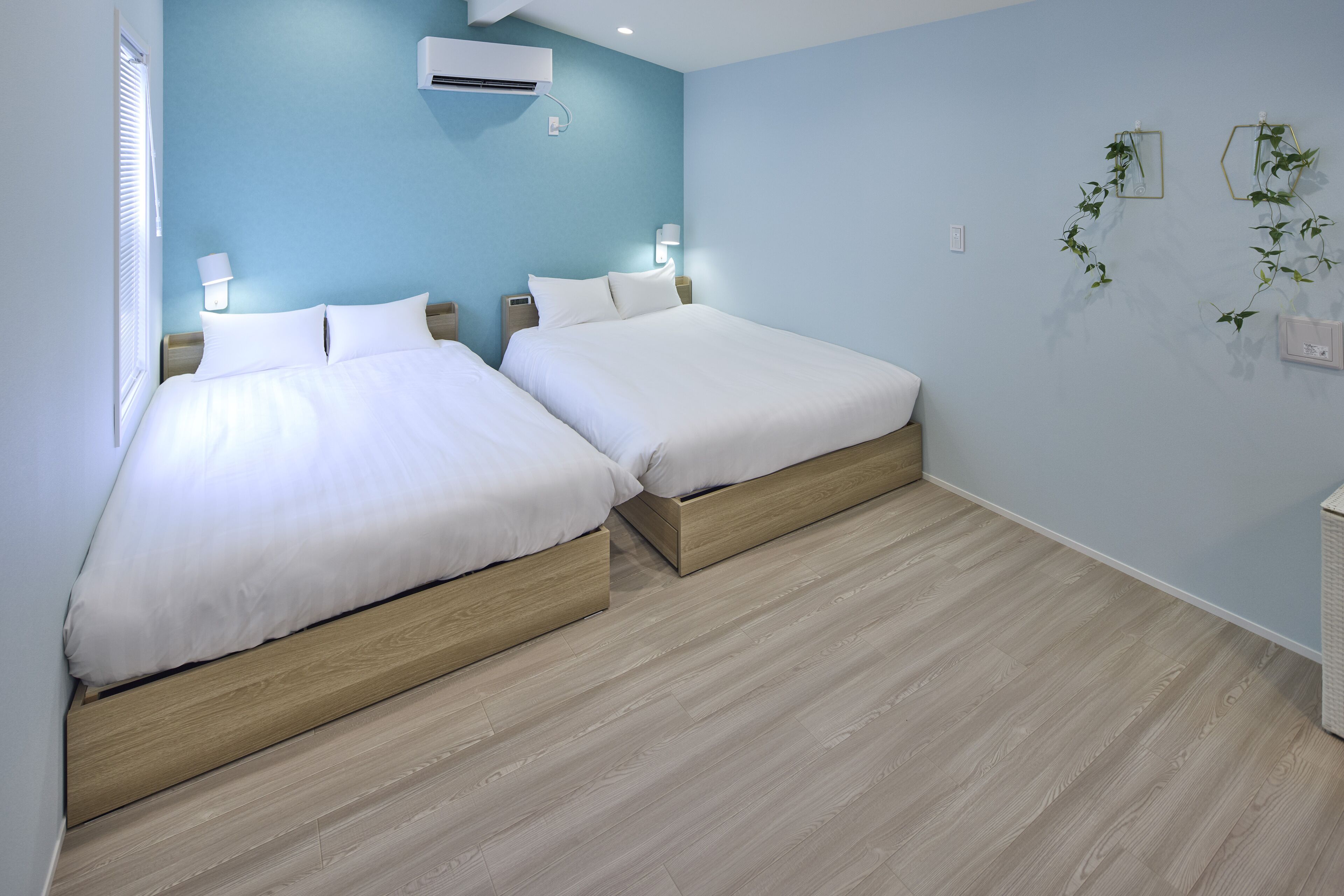 Une chambre avec deux lits, un climatiseur fixé au mur et une lampe fixée au mur.