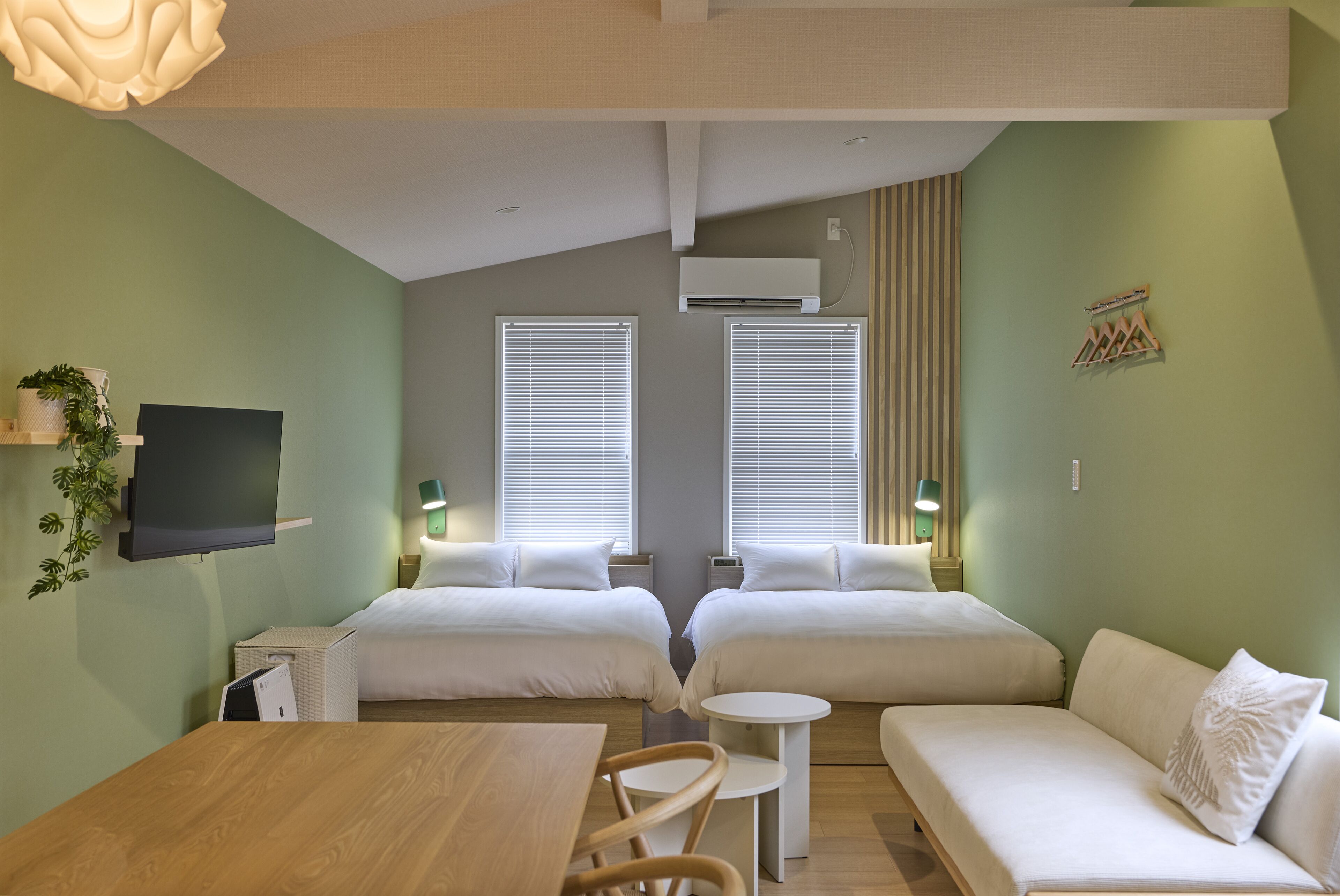 A room with two beds, a TV, a table, and a small round table.