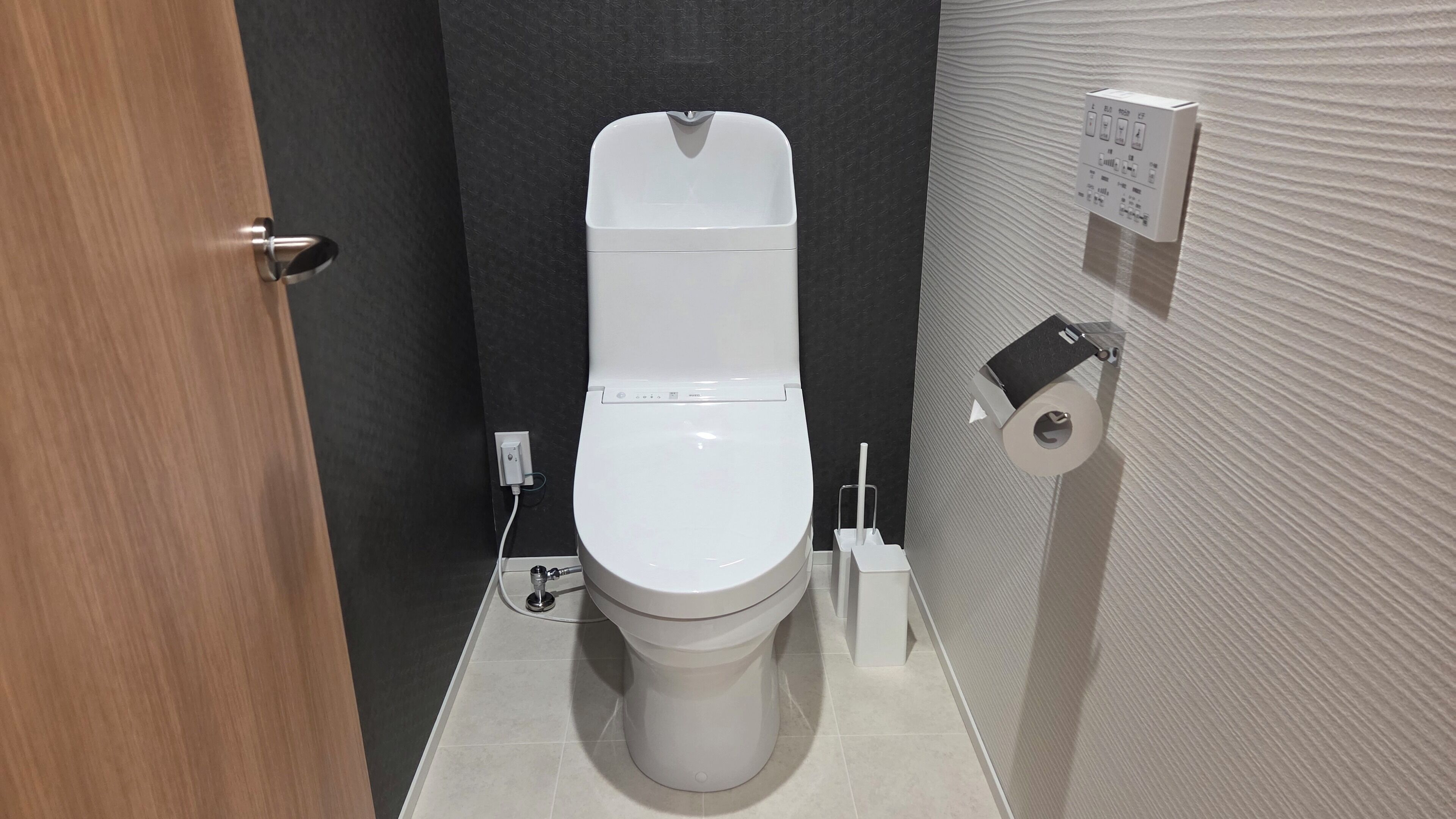 Un baño moderno con inodoro blanco, dispensador de toallas de papel y secador de manos.