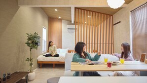 A modern interior with a wooden ceiling, a dining table with drinks, and a bed with a person sitting on it. - Solana Smart INN Fuji Gotenba  (Gotemba)