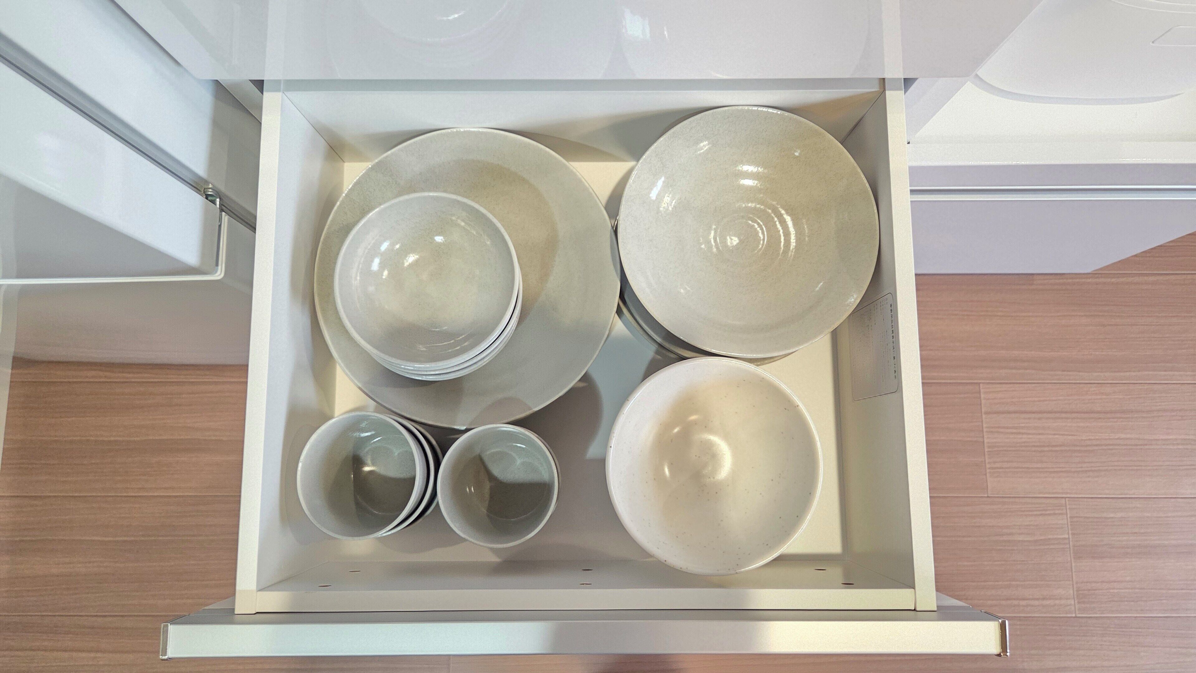 A kitchen drawer with various white ceramic dishes.