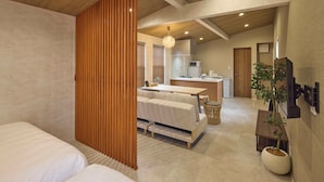 A modern hotel room with a large bed, a sofa, a dining area, and a kitchen in the background. - Solana Smart INN Fuji Gotenba  (Gotemba)