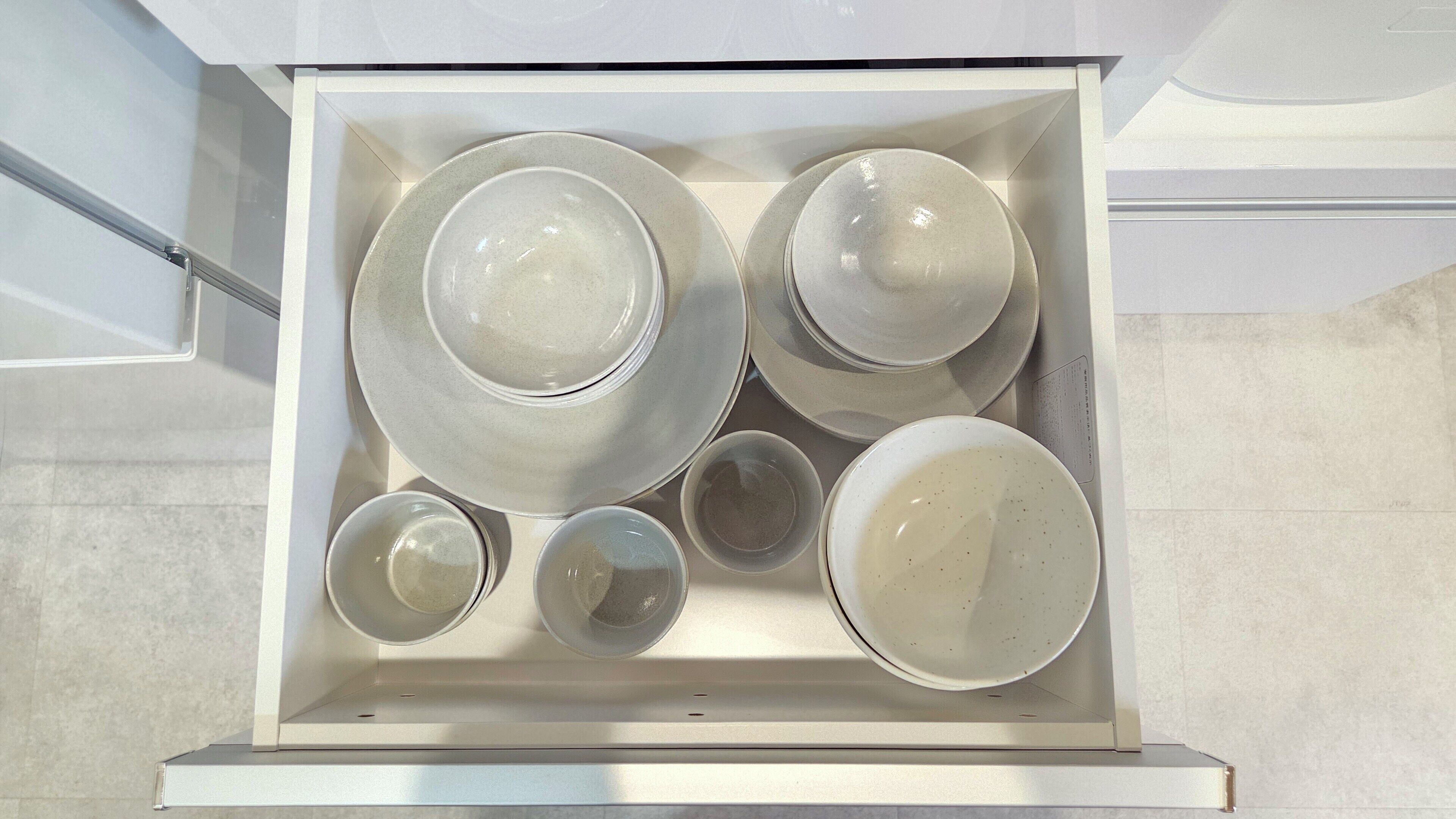 A drawer containing various ceramic dishes and bowls.