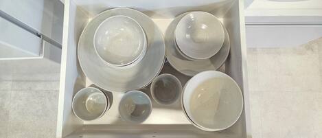 A drawer containing various ceramic dishes and bowls.