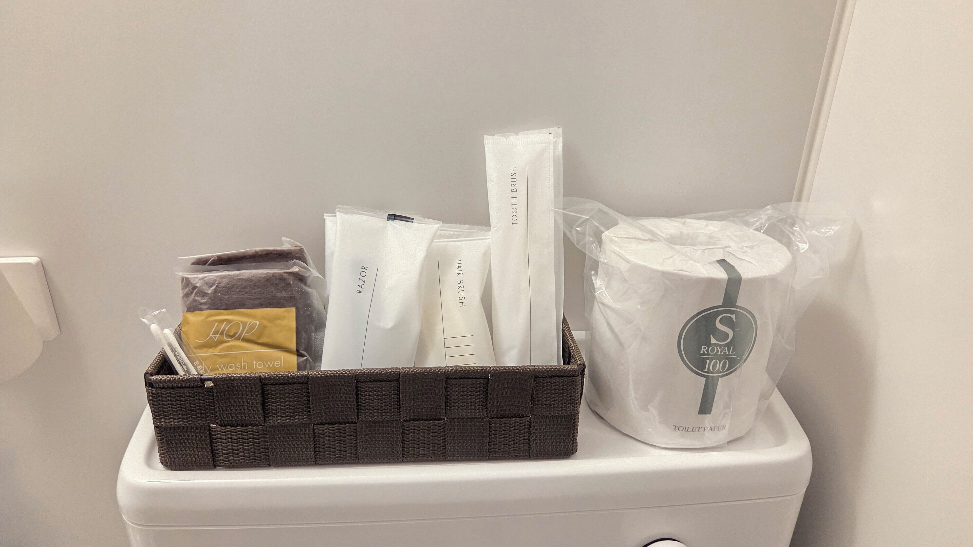 A bathroom with a white toilet, a basket containing toiletries, and a roll of toilet paper.