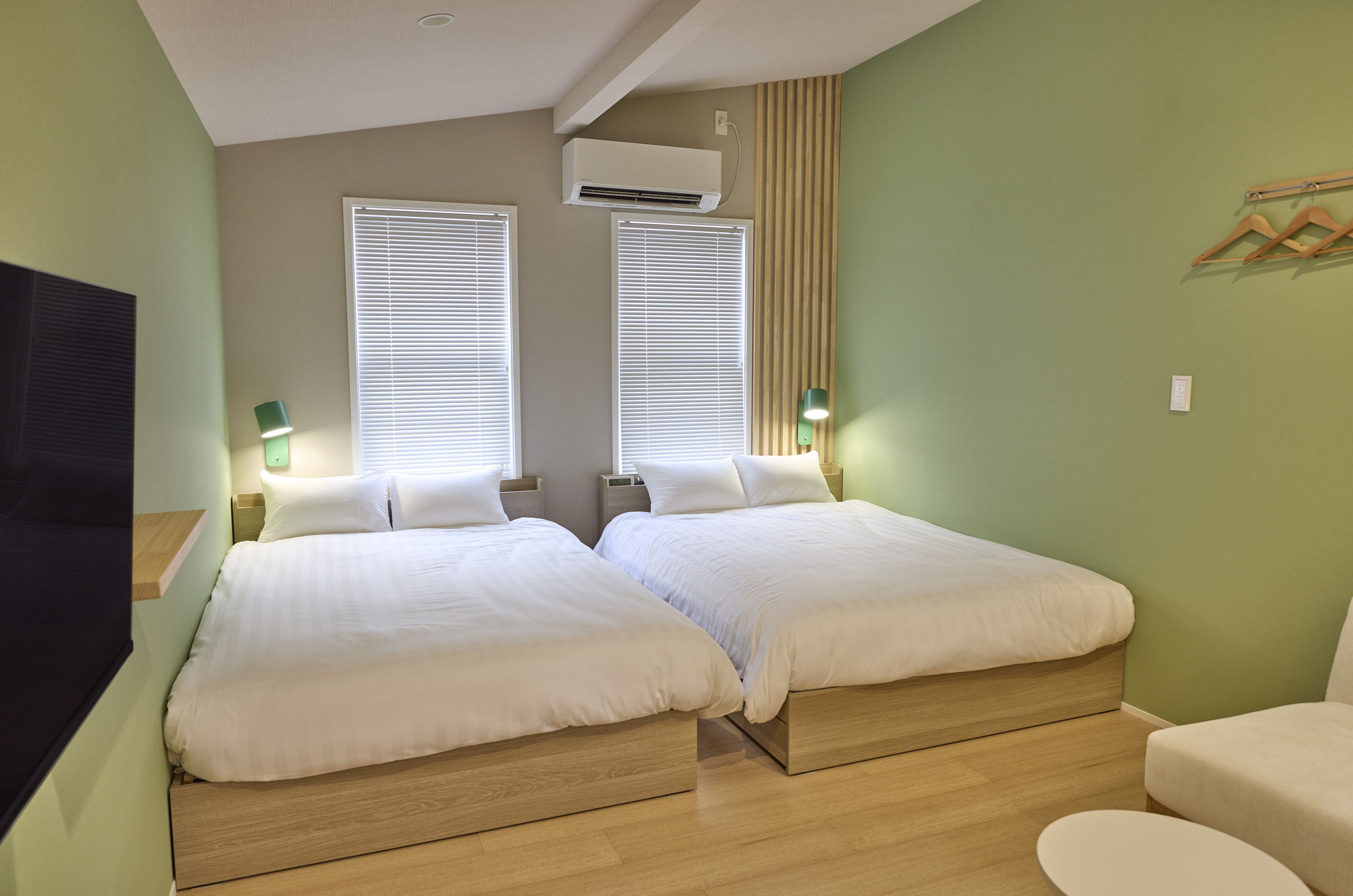 Habitación con dos camas, televisión y aire acondicionado de pared.