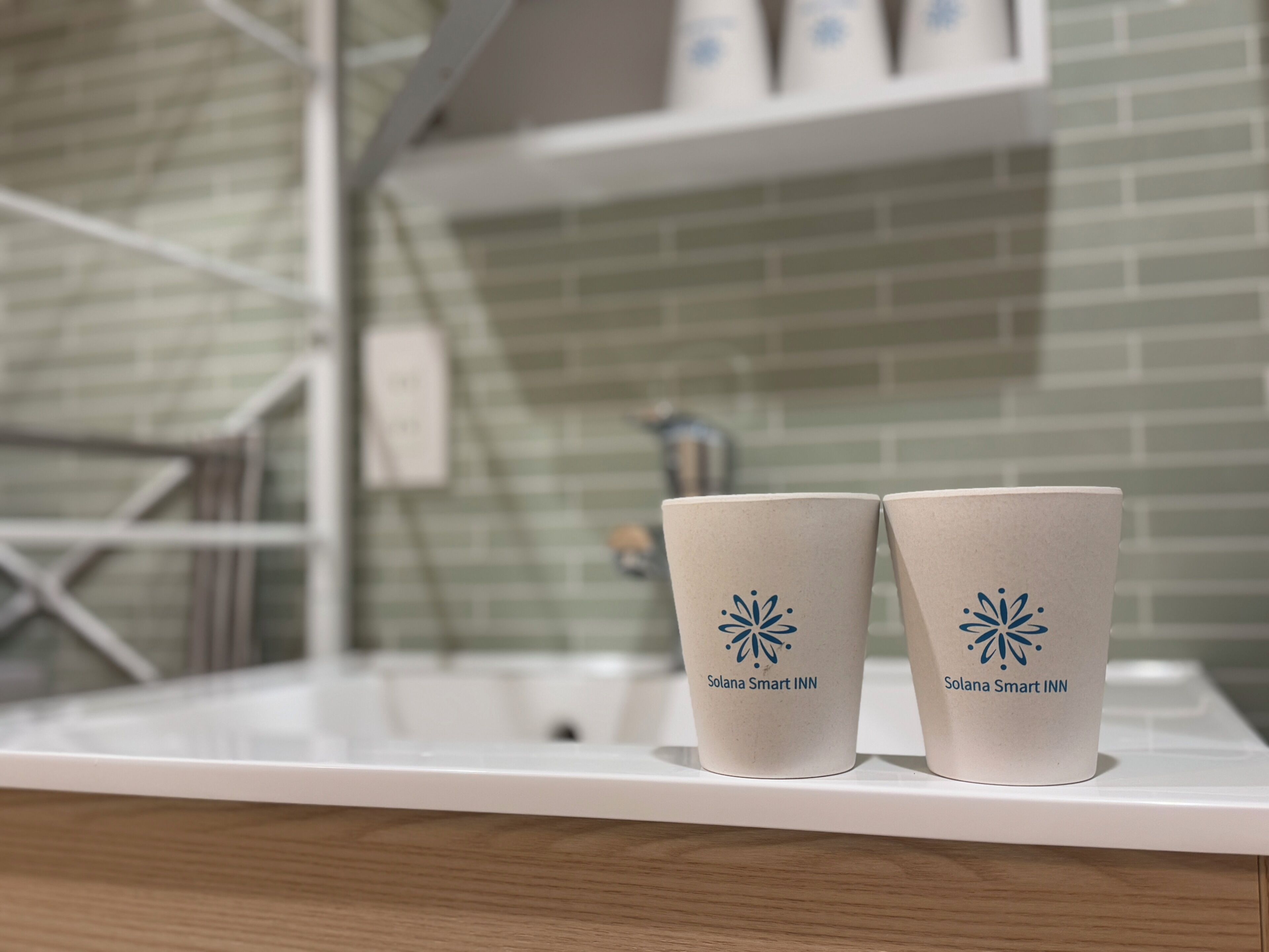 Two cups with a logo on a white countertop in a bathroom.
