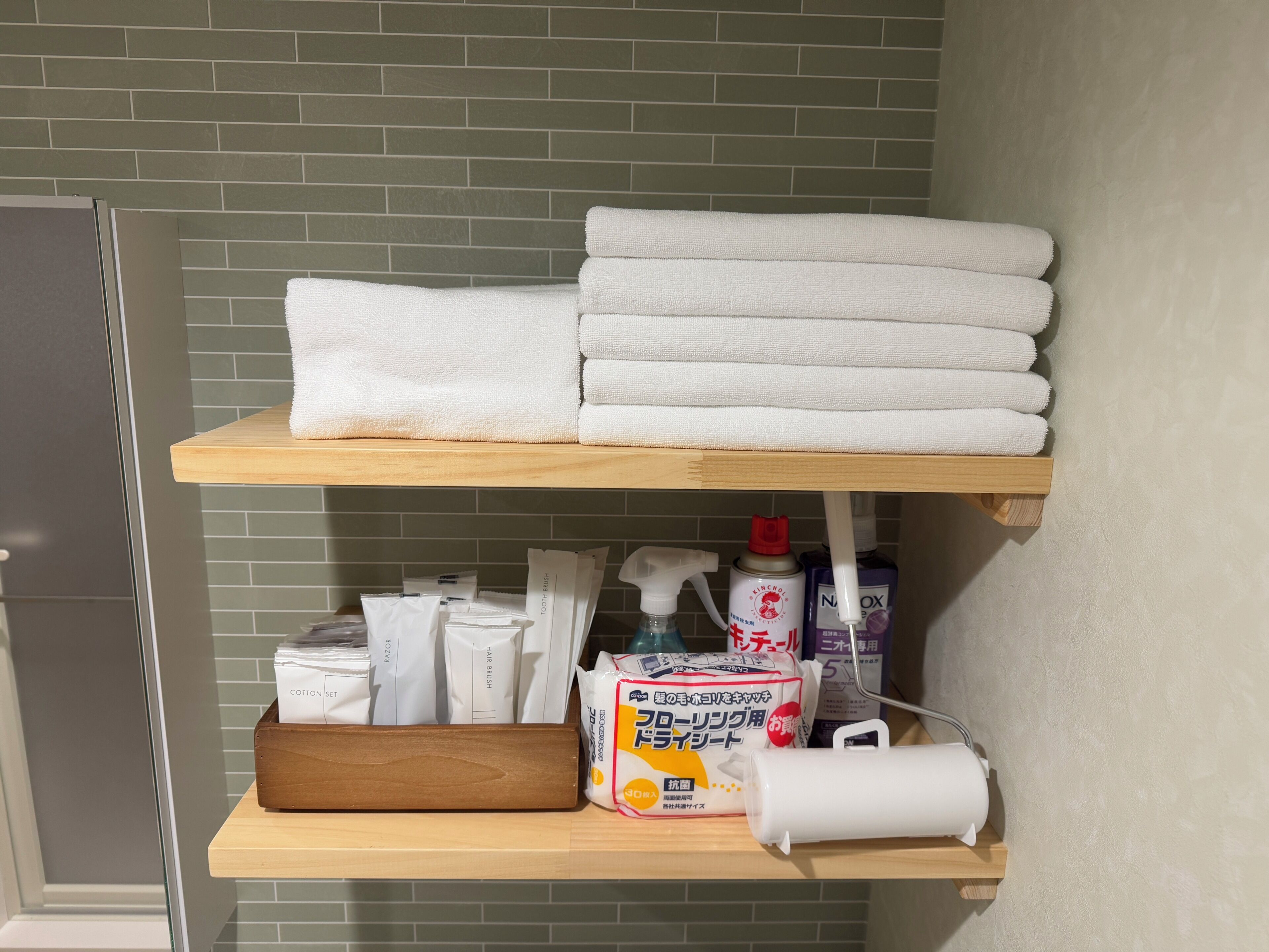 A bathroom with a towel rack holding folded towels, a shelf with toiletries, and a wooden box.