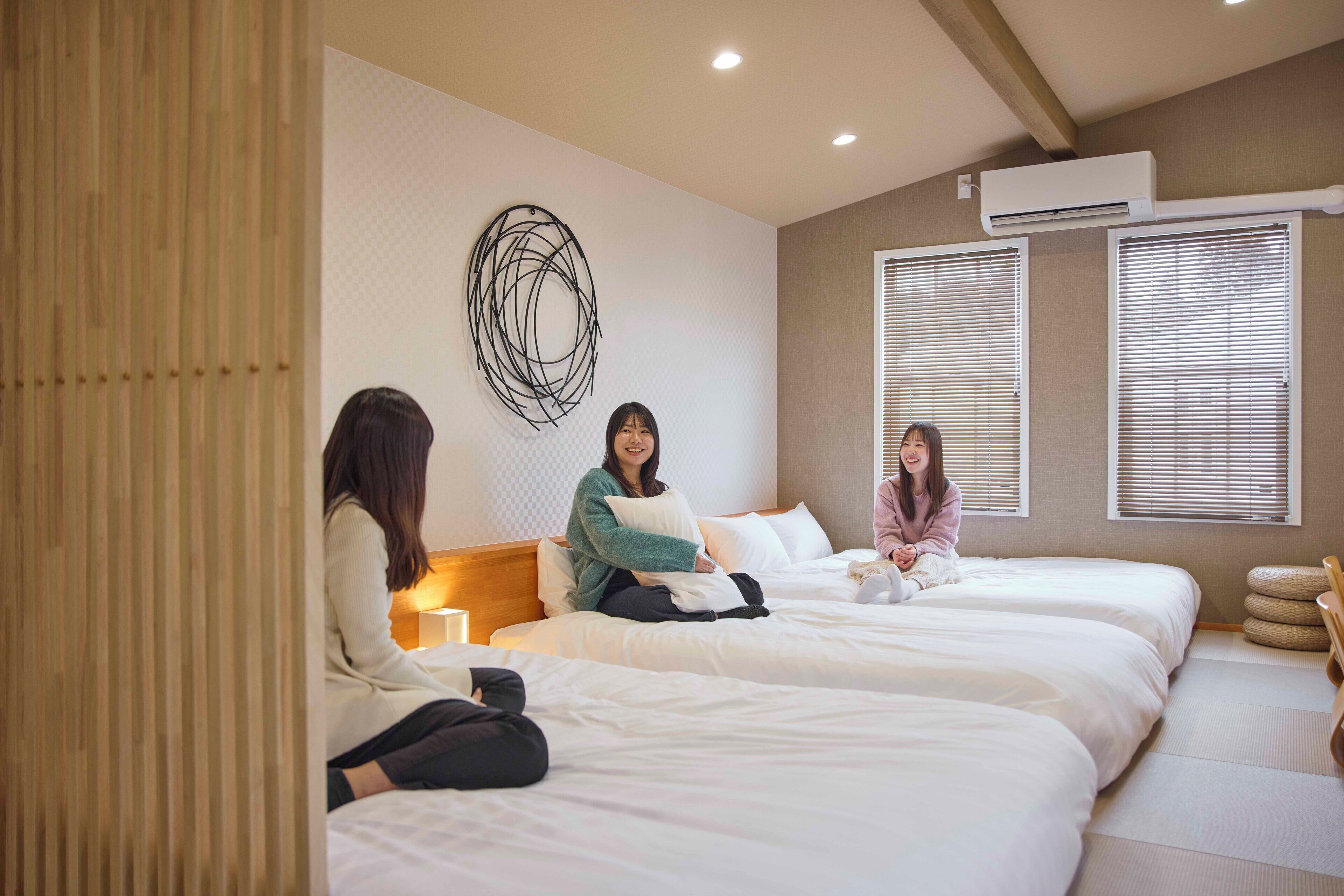 A hotel room with three beds, a wall art piece, and an air conditioning unit.