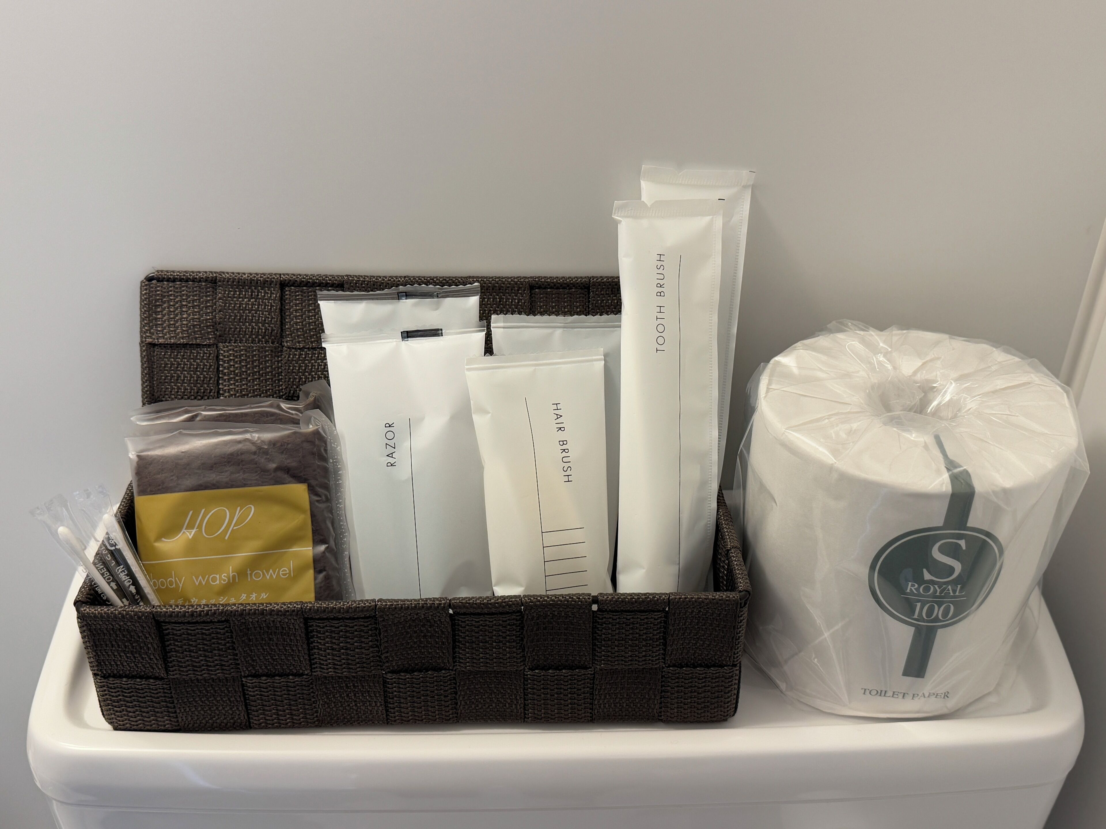 Un contenedor de almacenamiento con artículos de aseo personal, incluyendo maquinillas, cepillos para el cabello y papel higiénico.