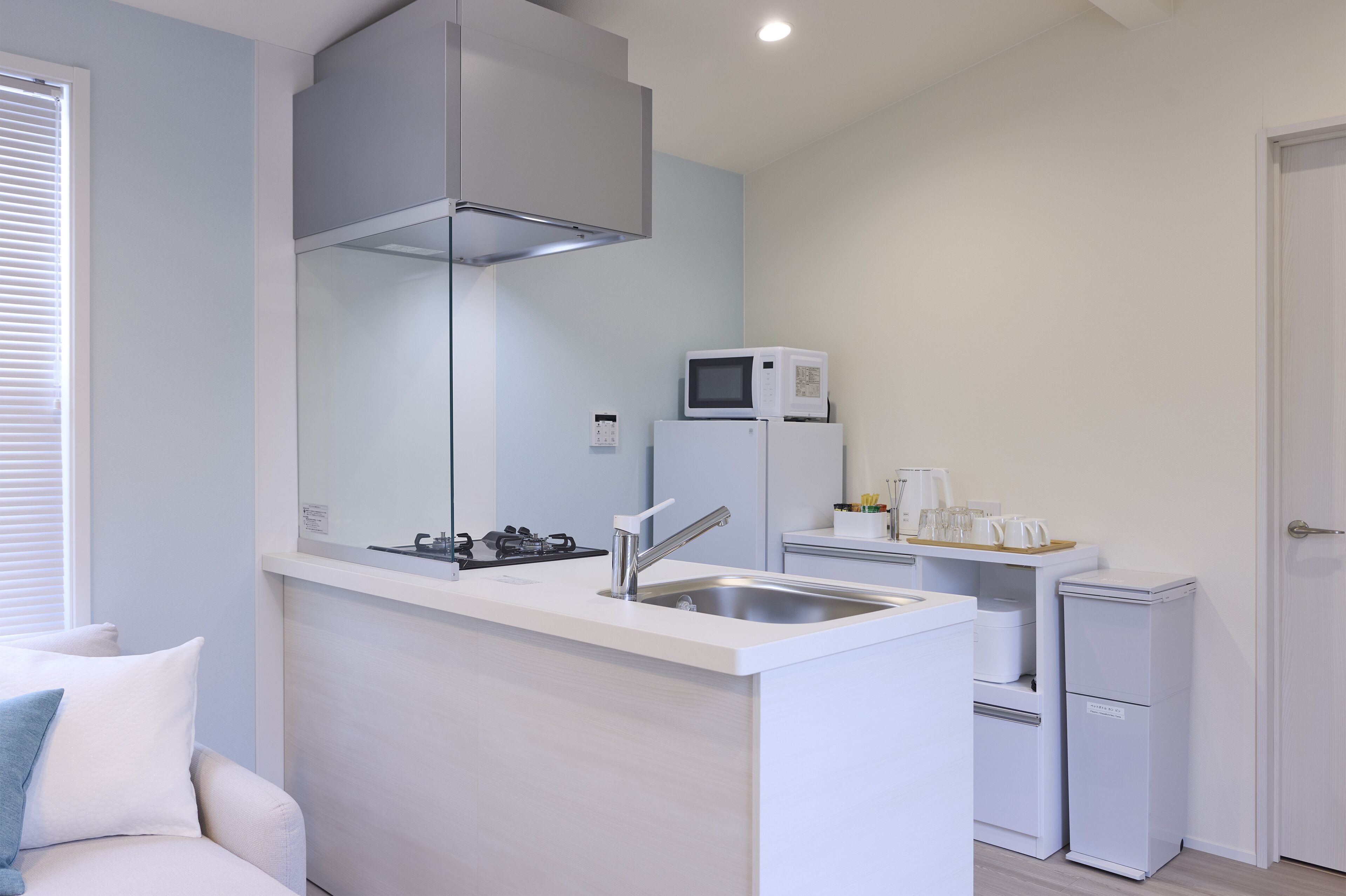 Una cocina compacta con estufa a gas, un fregadero, microondas y refrigerador.
