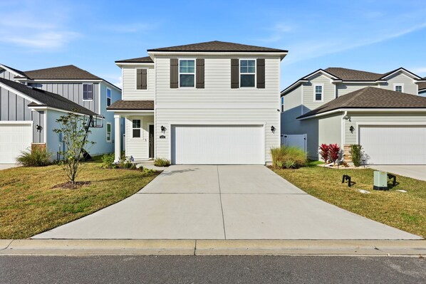 A suburban neighborhood with single-family homes featuring front garages and well-maintained lawns. - 4BR North Jax Peaceful Retreat, 8 minutes from Jax airport (Jacksonville)