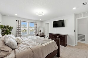 A bedroom with a bed, dresser, TV, and a window with curtains. - 4BR North Jax Peaceful Retreat, 8 minutes from Jax airport (Jacksonville)