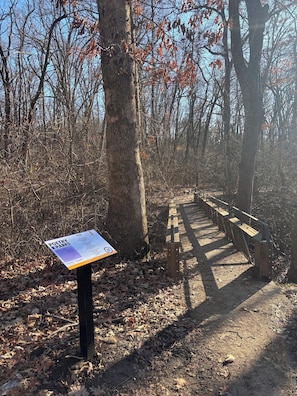 A sign for Poetry Parks with a wooden bench and trees in the background.