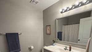 A bathroom with a toilet, sink, vanity, and a mirror with lights. - Tremendous 3-bedroom townhome with close to Cave Hollow Park in Warrensburg (Warrensburg)