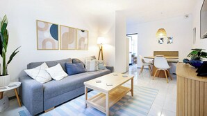 Una sala de estar moderna con un sofá gris, una mesa de centro de madera y un comedor con una mesa y sillas de madera.
