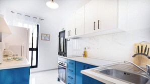 Una cocina moderna con armarios azules, un lavamanos de acero inoxidable y un horno empotrado.