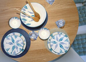 A round wooden table with a blue and white fish pattern dinnerware set, including plates, bowls, and a glass. - 2BR Penthouse with Large Front Terrace (St. Paul's Bay)