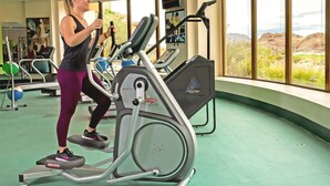 Ein Fitnessraum mit Laufbändern, Steppern und einem Fernsehbildschirm.