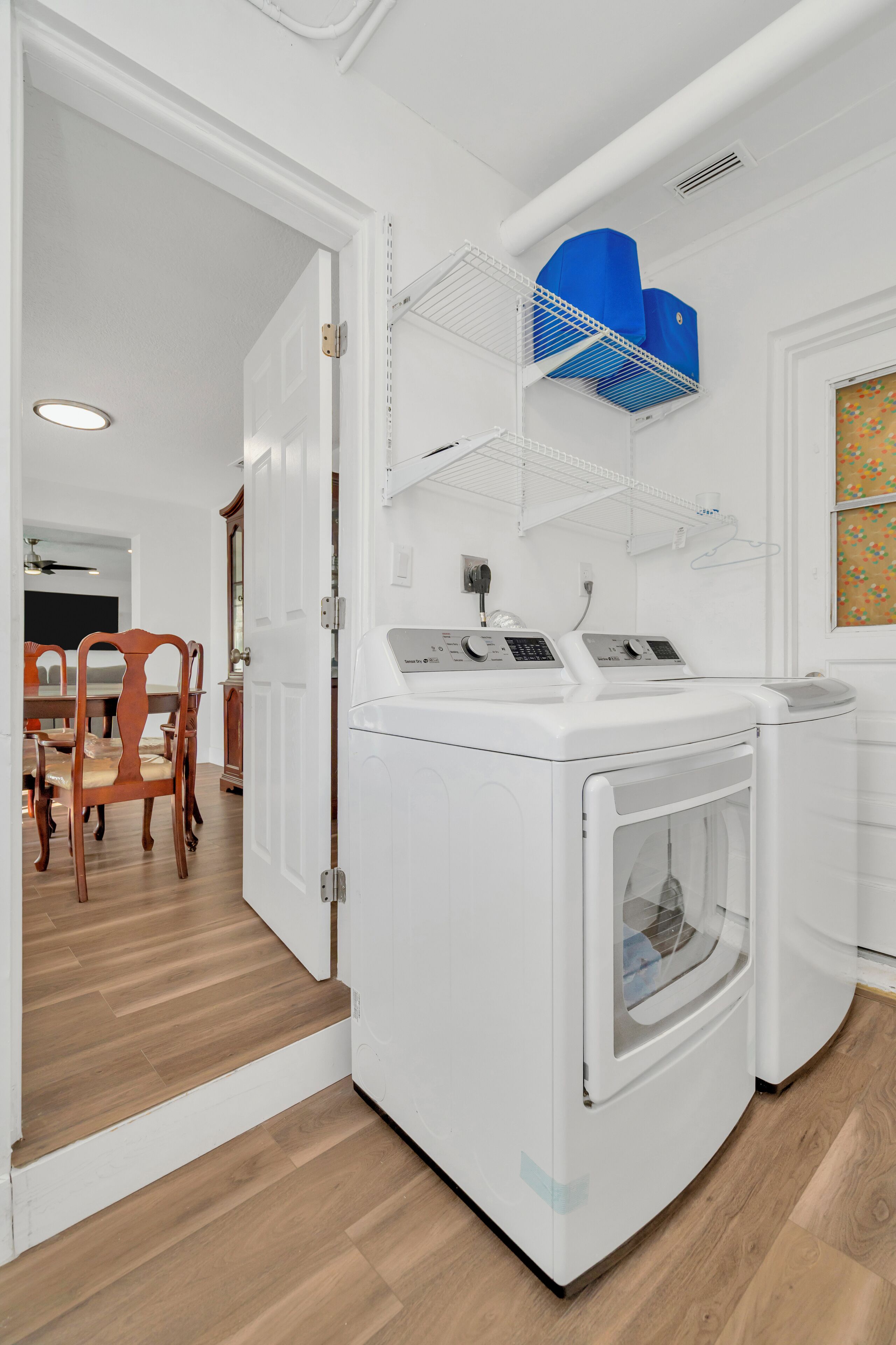 Une buanderie avec un lave-linge blanc, un sèche-linge et un ventilateur de plafond bleu.