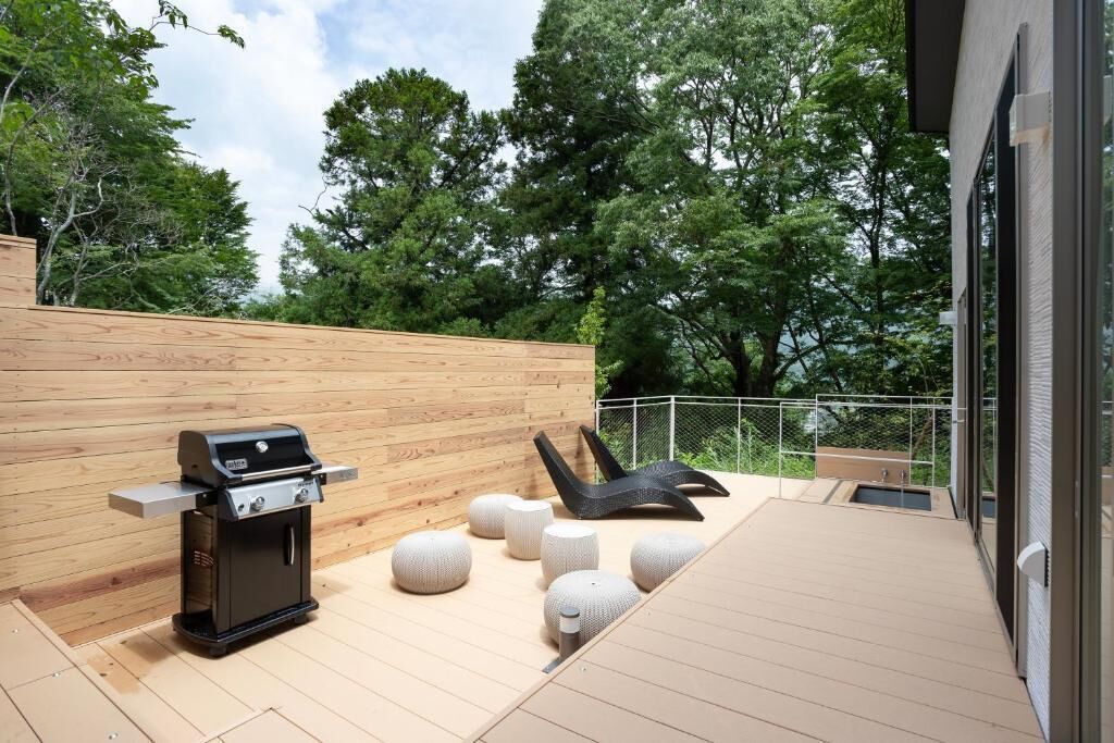 Une terrasse extérieure moderne dotée d’un barbecue intégré, d’un espace salon et de jardinières décoratives.