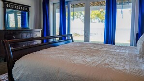 A bedroom with a bed, a dresser, a mirror, and a view through large windows. - Salty Bay Hideaway (Gulf Breeze)