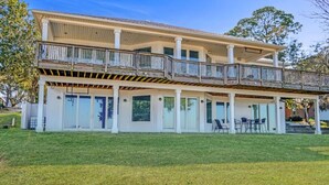 A two-story house with a covered patio, large windows, and a grassy yard. - Salty Bay Hideaway (Gulf Breeze)