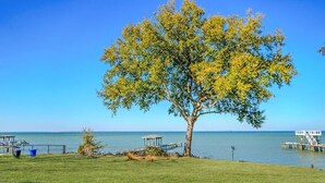 A tree-lined grassy area with a dock extending into a calm body of water. - Salty Bay Hideaway (Gulf Breeze)
