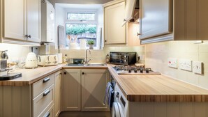 A modern kitchen with wooden cabinets, a built-in oven, a microwave, and a sink. - Beautiful 2 BD Cottage in the Cotswolds (Moreton-in-Marsh)