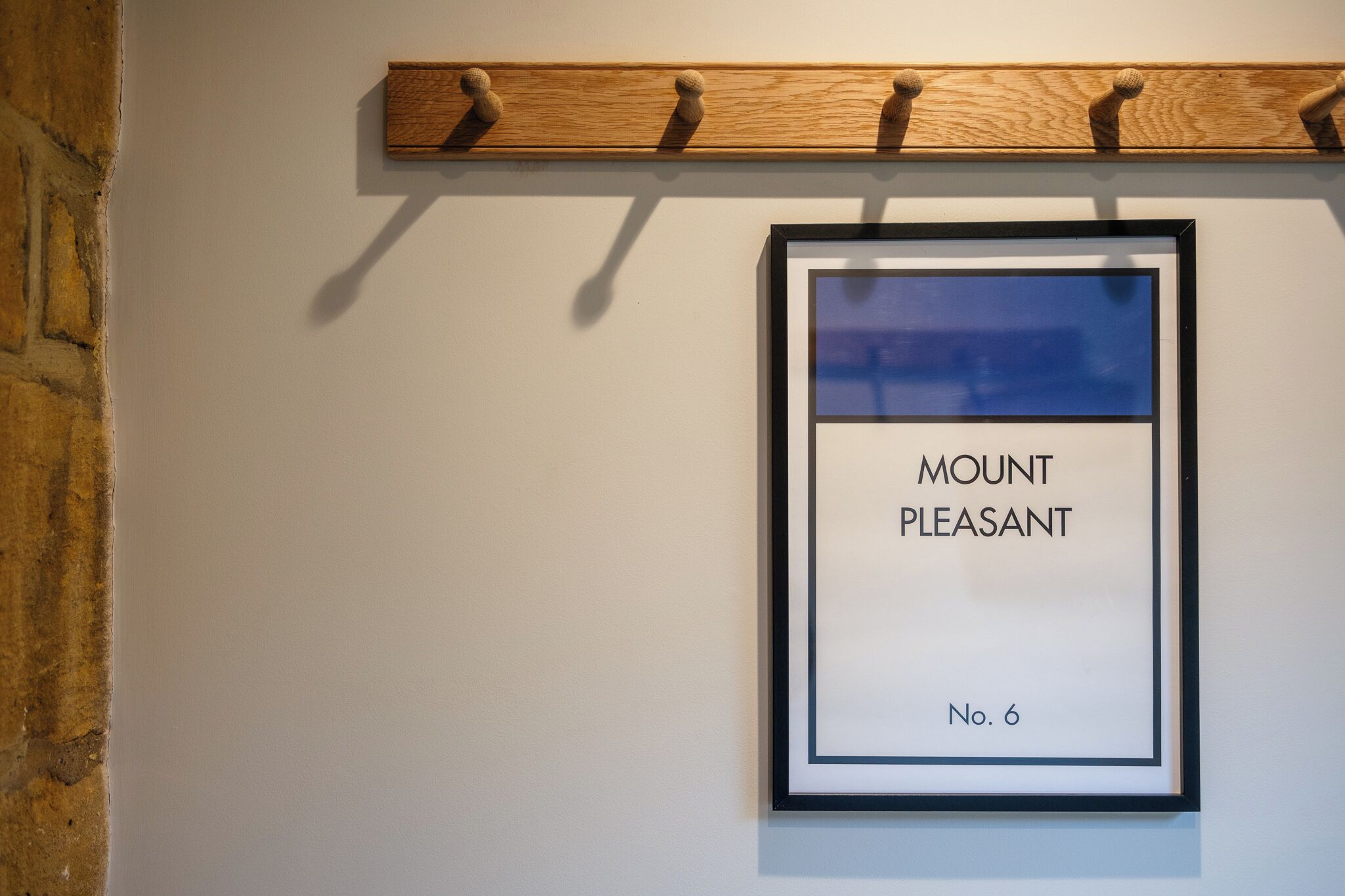 Une œuvre d’art encadrée intitulée « Mount Pleasant », avec une étagère en bois placée au-dessus.
