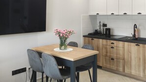 A modern kitchen with wooden cabinets, a black countertop, and a dining area with a table and chairs.