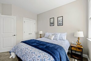 A bedroom with a bed, two bedside tables, a nightstand, and two framed pictures on the wall. - Lakefront Luxury - Beach, Dock, Deck @ Lake Anna (Mineral)