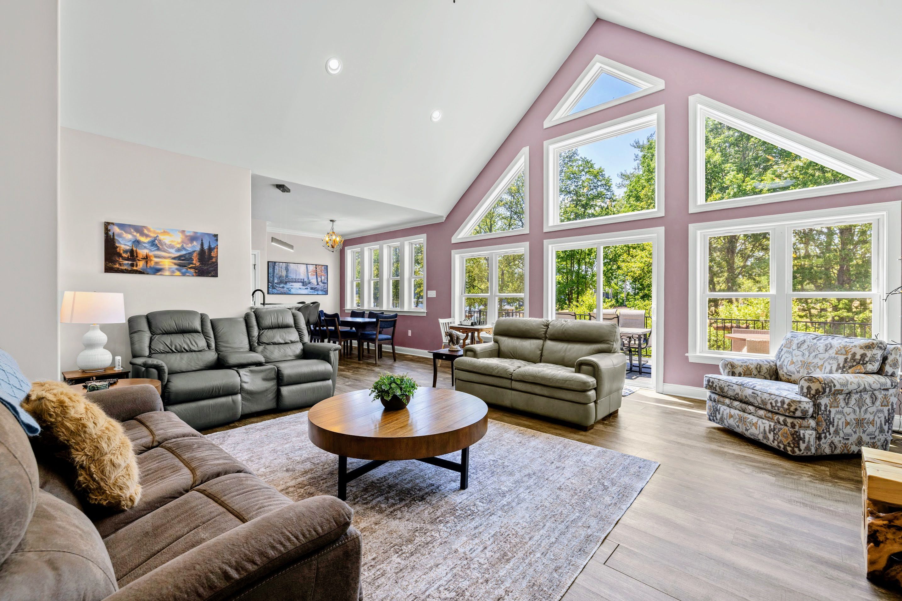 A spacious living room with a high ceiling, large windows, and a cozy seating area.