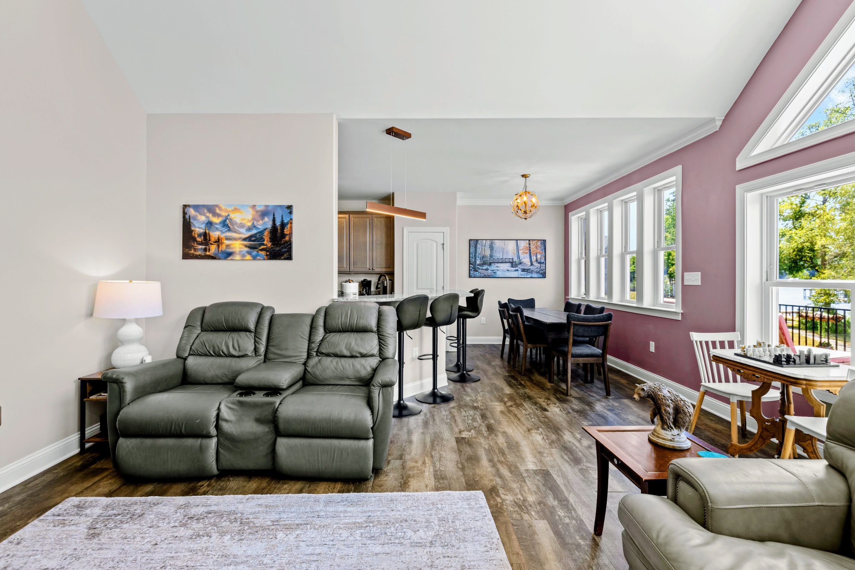 A living room with a sectional sofa, a dining area with a table and chairs, and a kitchen in the background.