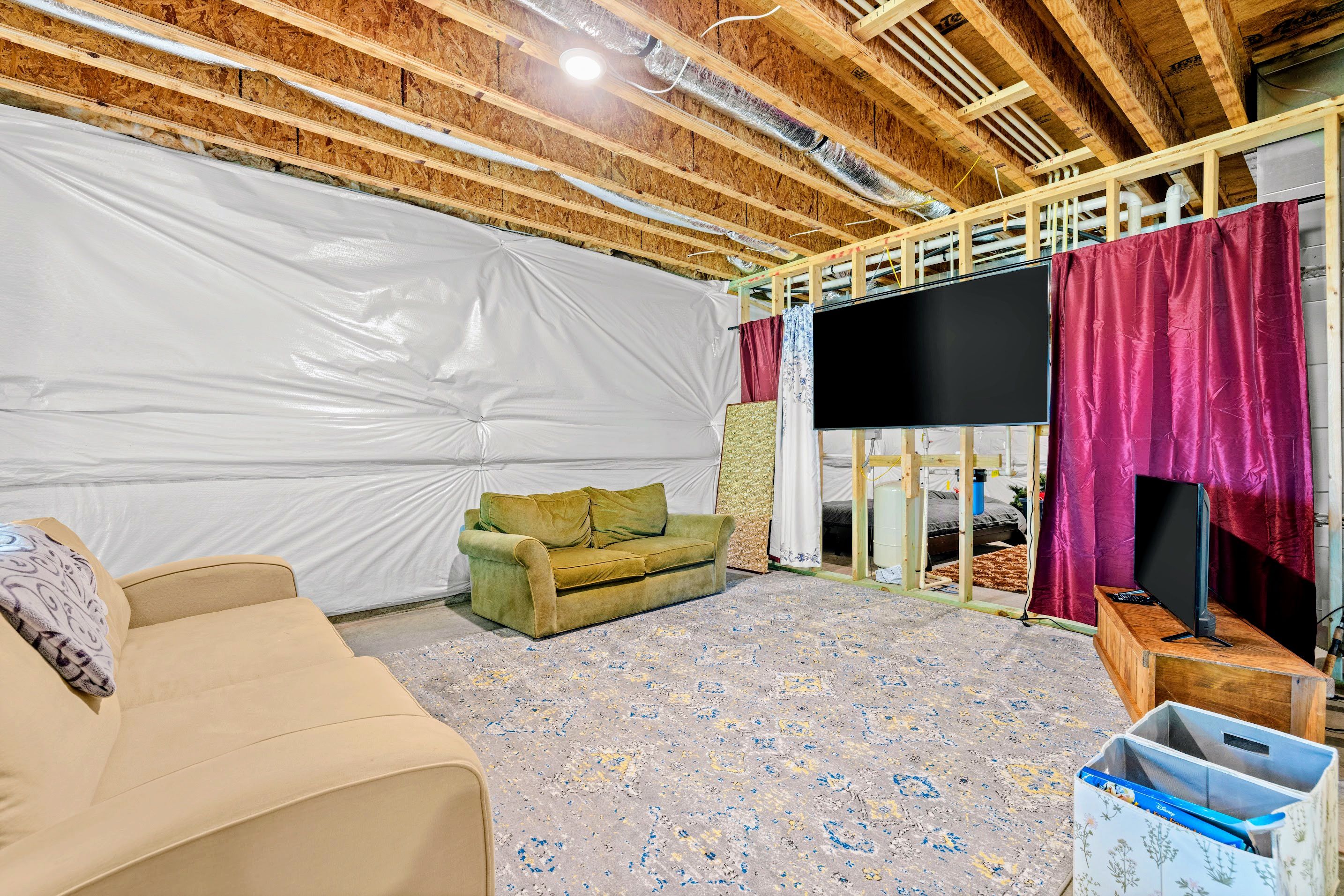 Une pièce avec un canapé, un téléviseur et une structure de plafond en bois.