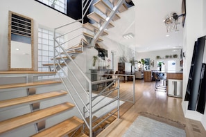 A modern interior with a central staircase, a dining area, and a kitchen. - Bohome Reserve:  Chicago Wicker Park • Sauna • Chef's Kitchen • Outdoor Lounging (Chicago)