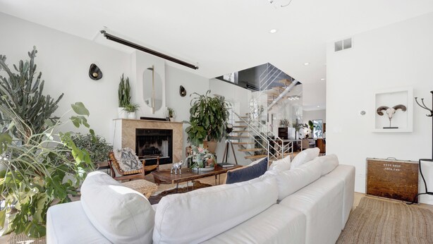 A modern living room with a white sofa, a fireplace, and various plants. - Bohome Reserve:  Chicago Wicker Park • Sauna • Chef's Kitchen • Outdoor Lounging (Chicago)