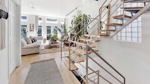 A spacious living area with a staircase, a sofa, and a coffee table. - Bohome Reserve:  Chicago Wicker Park • Sauna • Chef's Kitchen • Outdoor Lounging (Chicago)