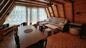 L’intérieur d’un chalet accueillant, avec une table à manger en bois, un canapé et une petite table.