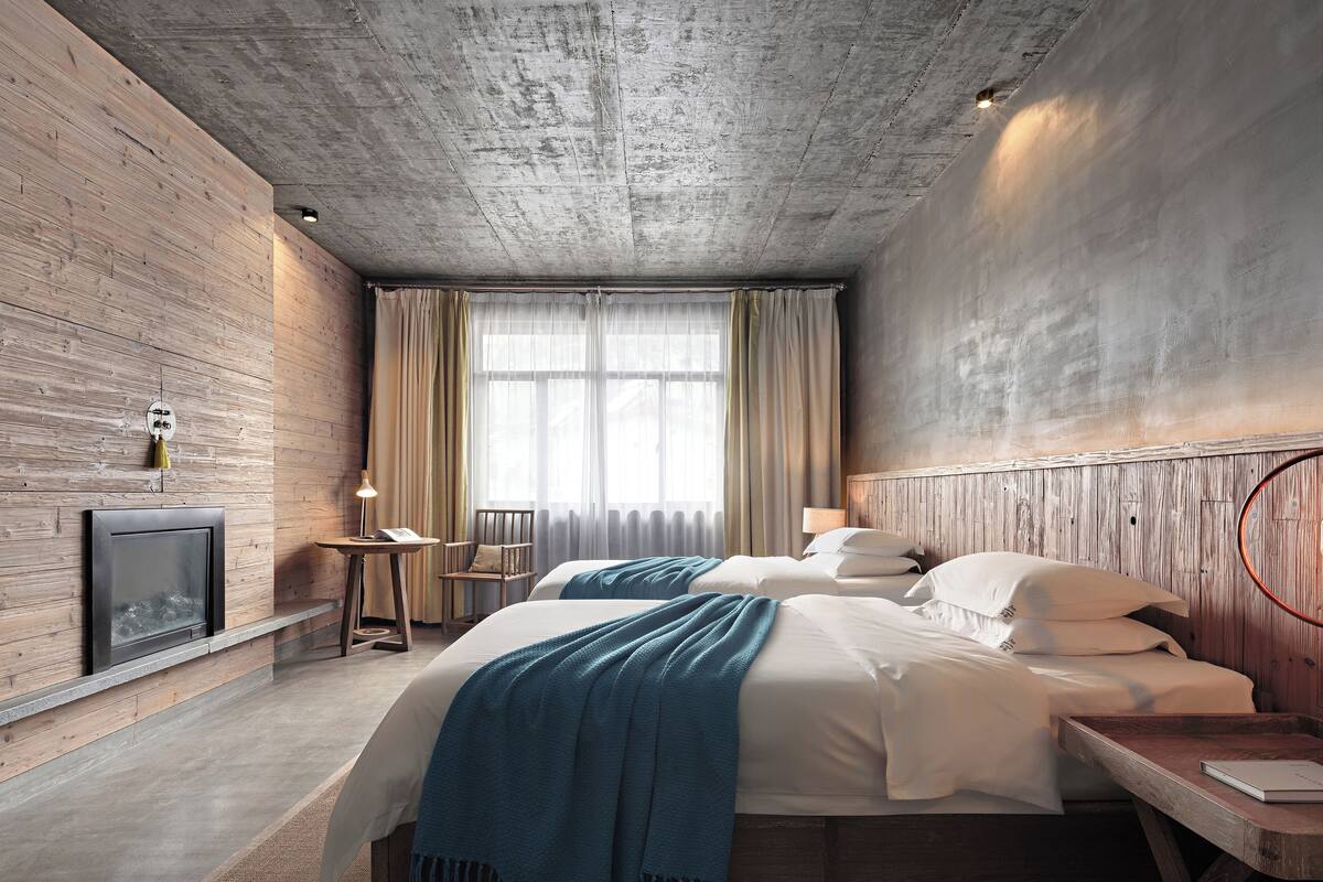 Habitación de hotel moderna con diseño rústico, que incluye una cama grande, una mesita, una silla y una chimenea.