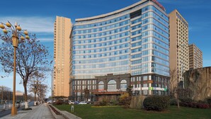 A modern hotel with a curved facade, multiple floors, and a prominent 'Hampton' sign.